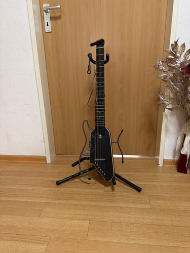 Customer's Donner HUSH I Reisegitarre auf einem Ständer vor einer Holztür.