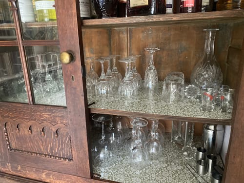 Customer's sage green William Morris drawer liners lining a wooden Welsh dresser filled with glassware