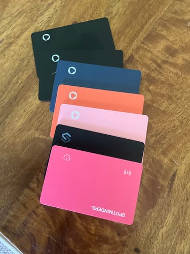Customer's collection of colorful, thin Spotminders Tracking Cards stacked on a wooden surface.