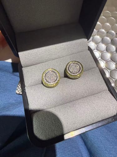 Reviewer's pair of iced round moissanite stud earrings resting in a black gift box