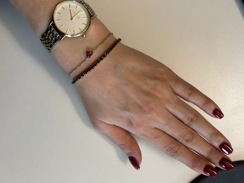Customer's Valentine’s Day Gift heart bracelet on a wrist stacked with other bracelets and a watch.