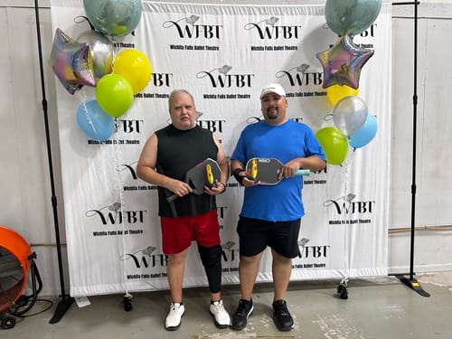 Customer's white CUURT Muuv court shoes worn by two people holding pickleball paddles in front of a banner.