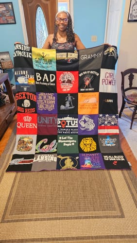 Customer's Project Repat T-Shirt Quilt held up, displaying a vibrant patchwork of various colorful t-shirt logos.