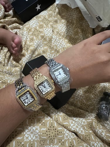 Customer's hand wearing three Grealy De Mains watches with metallic silver and gold tones on a patterned blanket.