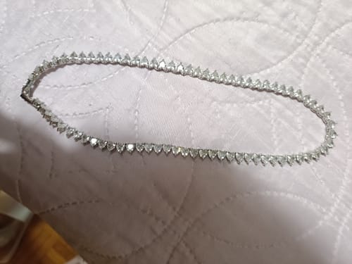 Customer's Collana tennis con cuori in zirconi adagiata su una superficie trapuntata bianca