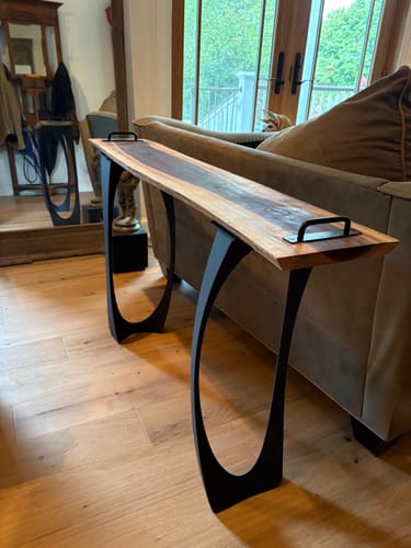 Customer's Console Table Legs Cleo installed on a live edge wooden tabletop in a living room.