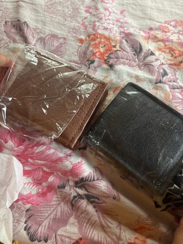 Customer's two plain, wrapped wallets on a floral surface, instead of the ordered Spiderman wallet.