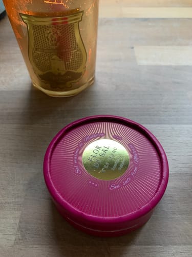 Kundenfoto des Flor de Sal d'Es Trenc Rote Beete Salzes in seiner runden, pinkfarbenen Dose auf einem Holztisch.