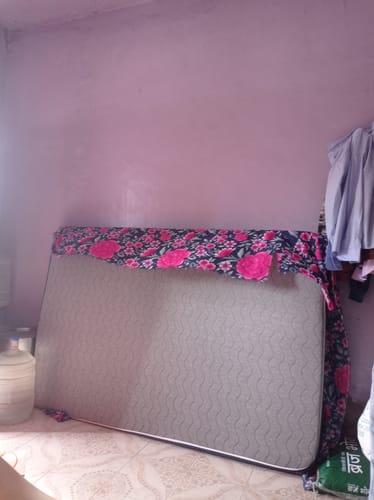 Customer's Flo Mattress Ortho leaning against a purple wall, partially covered with a floral cloth.