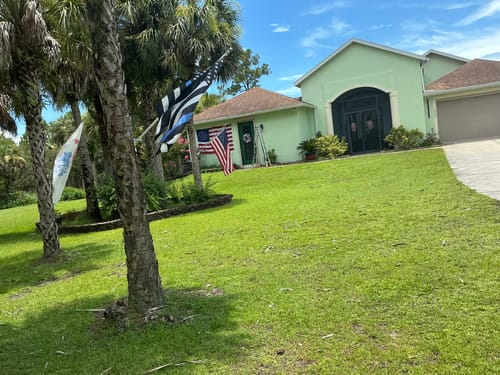 Reviewer's Heavy Duty American Nylon Flag flying outside a house on a lawn.