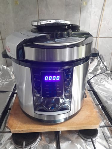 Customer's stainless steel Novio SteelCook multicooker on a wooden board, showing the digital control panel.