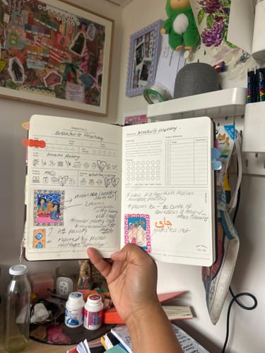 Reviewer holding an open Chocolate Brown Craft Project Planner with written notes, stickers, and creative planning pages.