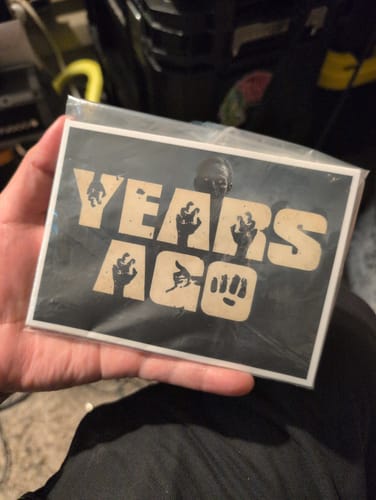 Customer's custom die-cut decal held in hand, showing black and cream text graphic inside a protective plastic sleeve.