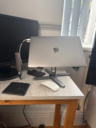 Reviewer's silver Model-X 2.0 Stand holding a laptop on a desk with a mouse and monitor nearby.