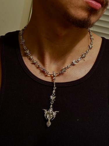 Customer's silver Rotten Rosary necklace worn around the neck against a black shirt.