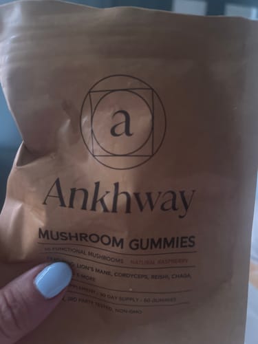 Customer's hand holding a brown pouch of Ankhway Mushroom Gummies in a close-up.