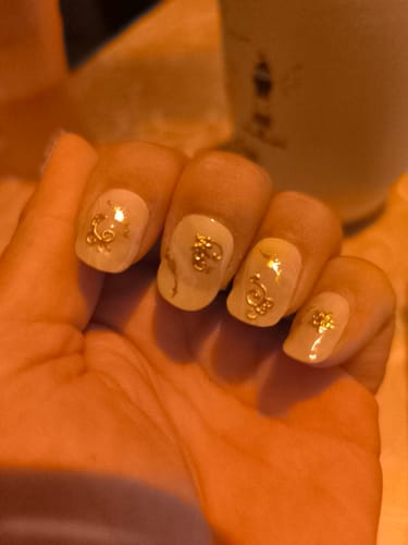 Kundenfoto der UV Gel Nail Wraps Vanilla Marble an einer Hand mit beigen Nägeln und goldenen Verzierungen.