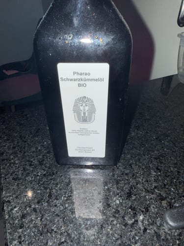 Customer's bottle of Pharao Schwarzkümmelöl BIO on a dark countertop.
