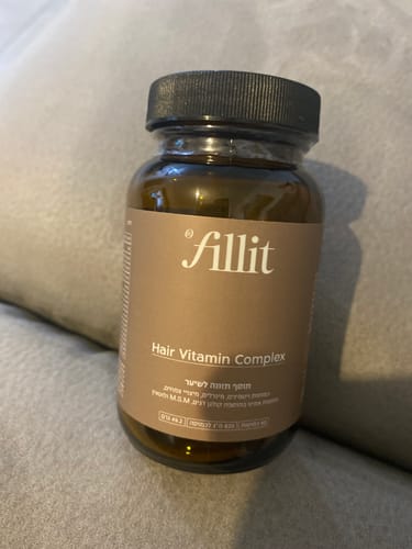 צנצנת חומה של תוסף הויטמינים Fill it Hair Complex המונחת על משטח אפור