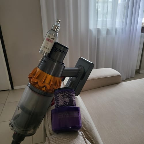 Customer's Essenza Igienizzante Cotone D'Aurora bottle resting on a vacuum cleaner filter on a couch.