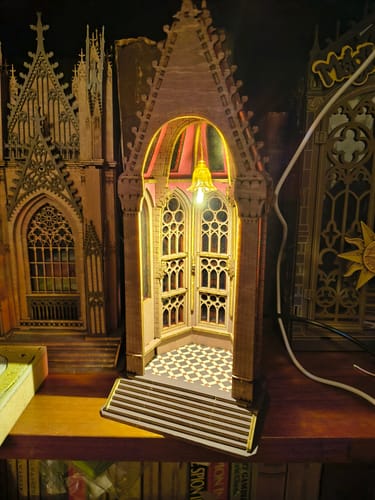 Customer's verlichte Robotime Geometric Cathedral bouwpakket met gedetailleerde ramen en geruite vloer op een plank.