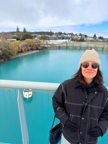 Customer's Women's Black Boxy Workwear Heritage Contrast Stitching Snow Jacket worn on a bridge over blue water.