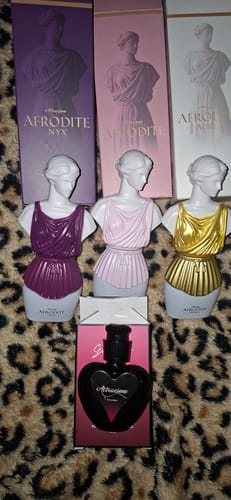 Customer's Kit Afrodite perfumes with bust-shaped bottles and heart-shaped Attracione fragrance on patterned fabric.