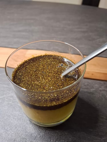 Customer's Brennnesselsamen scattered on top of a liquid in a glass with a spoon.