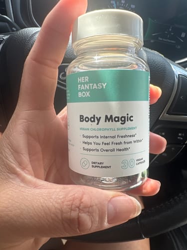Reviewer's hand holding a bottle of Body Magic Chlorophyll Supplement in a car, showing the label clearly.