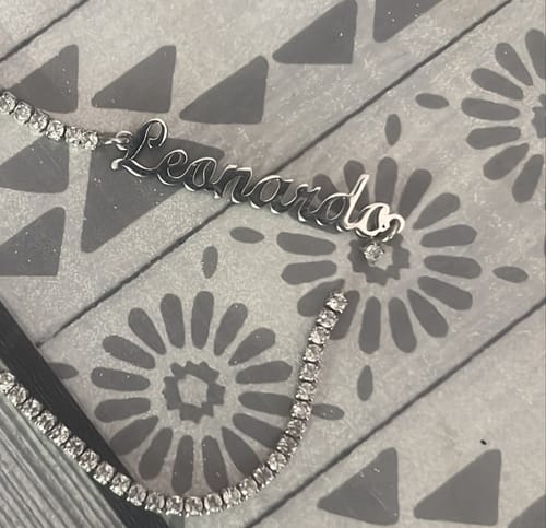 Customer's broken tennis bracelet with name Leonardo in cursive, showing a detached link and sparkling crystals.