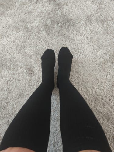 Customer's black Diasocks Stödstrumpor worn on legs against a light carpet background.
