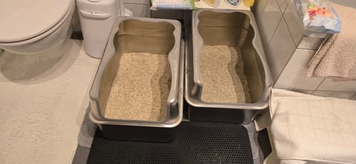 Customer's Naturreines Katzenstreu in zwei silberfarbenen Katzentoiletten in einem Badezimmer.