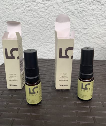 Reviewer's packaging for CBD Öl 5%, showing two spray bottles and boxes on a textured surface.