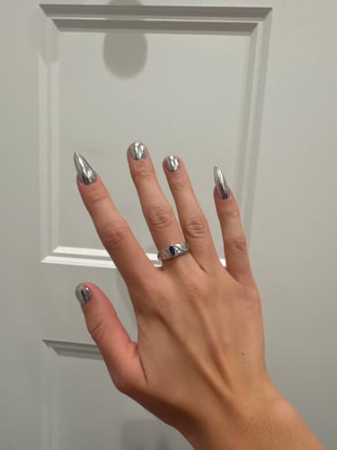 Customer's Birthstone Ring on finger, featuring a deep blue stone with botanical silver detailing.