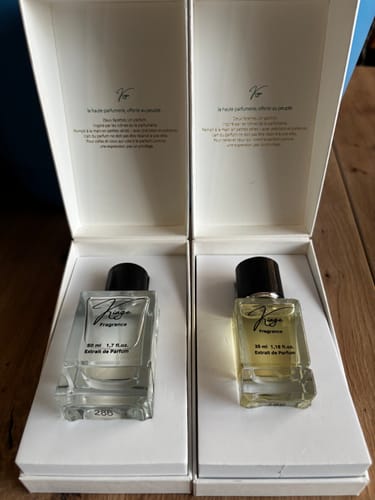 Kundenfoto der 1x 35ml und 1x 50ml Parfümflaschen, die in ihren geöffneten, eleganten Boxen auf einem Holztisch stehen.