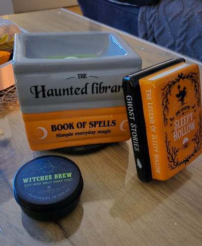 Customer's Halloween Duftlampe Bücherstapel und ein Witches Brew Wachsschmelzer auf einem Holztisch.
