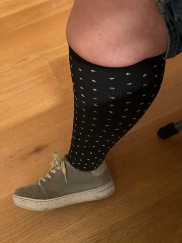 Customer's black FlowFit Oversize Kompressionssocken worn on the lower leg with a grey sneaker.