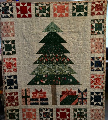 Customer's completed Presents & Pines quilt featuring a central Christmas tree with Nutcracker fabrics and star border.
