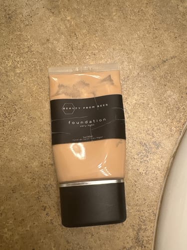 Customer's Beauty From Bees foundation tube, resting on a beige surface.