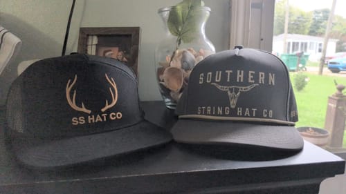 Customer's Hat of the Month Crew caps featuring antlers and bull skull logos on a dark surface.