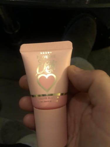 Customer's hand holding a pink tube of The Cheek Of It Liquid Blush