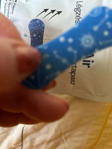 Customer's hand holding a blue EasyAir nose strip, with the product packaging visible in the background.