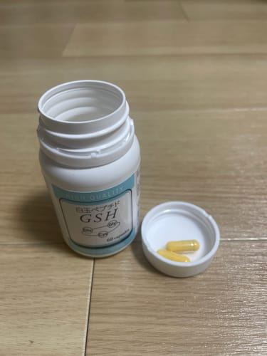 レビューアのワカサプリ 白玉ペプチド（GSH）のボトルと、キャップに入った黄色いカプセル2粒。