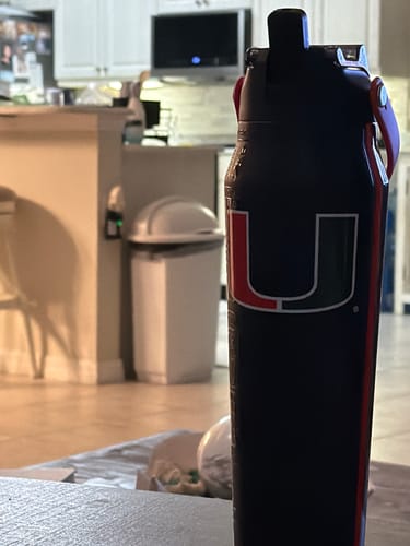 Customer's black Miami Hurricanes Bottle Buddy 32oz, standing in a kitchen setting.
