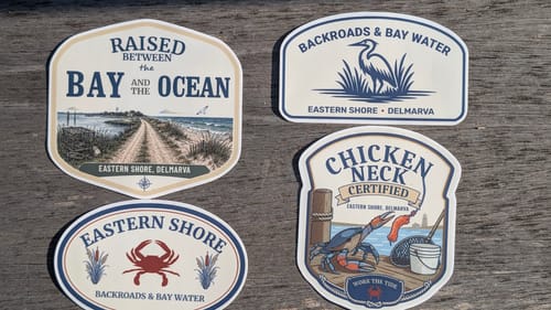 Customer's four custom vinyl stickers with various designs featuring coastal and nautical themes, laid on a wooden surface.