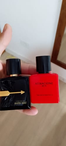 Customer's hand holding black Adonis Goat and red Attracione Men perfume bottles.