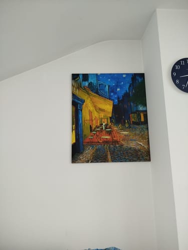 Customer's Terrazza del caffè la sera print hanging on a white wall next to a dark blue clock.