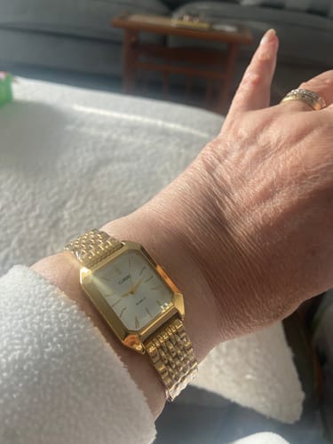 Customer's gold Claire De Mains watch with a metal link band worn on a person's wrist.