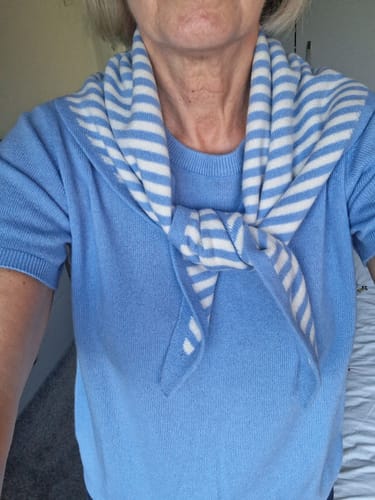 Customer's cornflower and white striped cashmere scarf tied around their neck over a matching blue shirt.