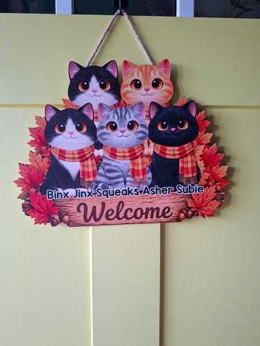 Customer's personalized Fall Cats Welcome door sign hanging on a yellow door, featuring five cartoon cats and autumn leaves